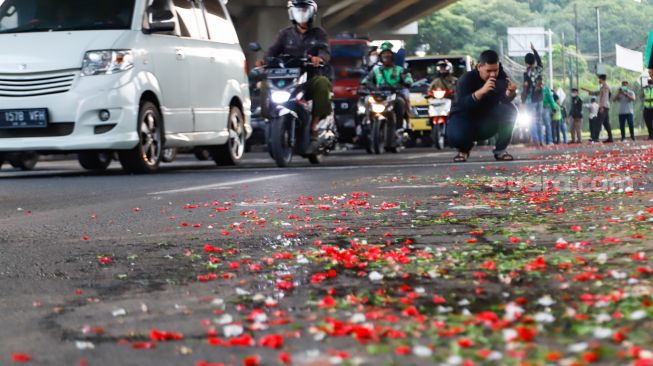 Warga sekitar saat menggelar aksi tabur bunga di Jalan Transyogi Cibubur, Bekasi, Jawa Barat, Rabu (20/7/2022). [Suara.com/Alfian Winanto]